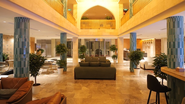 A spacious lobby with a central sofa, seating areas, potted plants, and a mezzanine level. - Poykent Bukhara Old City (Bukhara)