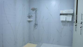 A bathroom with a shower, a towel rack, and a shelf with toiletries.