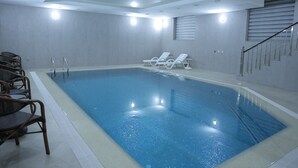 An indoor swimming pool with clear water, surrounded by lounge chairs and a staircase. - Poykent Bukhara Old City (Bukhara)