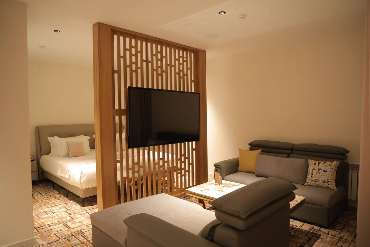 Een hotelkamer met een bed, een bank, een televisie en een bijzettafeltje.
