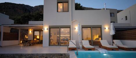 En modern villa med pool, utomhusmöbler och en matplats.