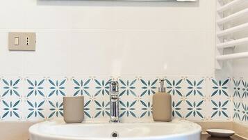 Un baño con un lavamanos blanco, un espejo encima y una pared con azulejos azules.