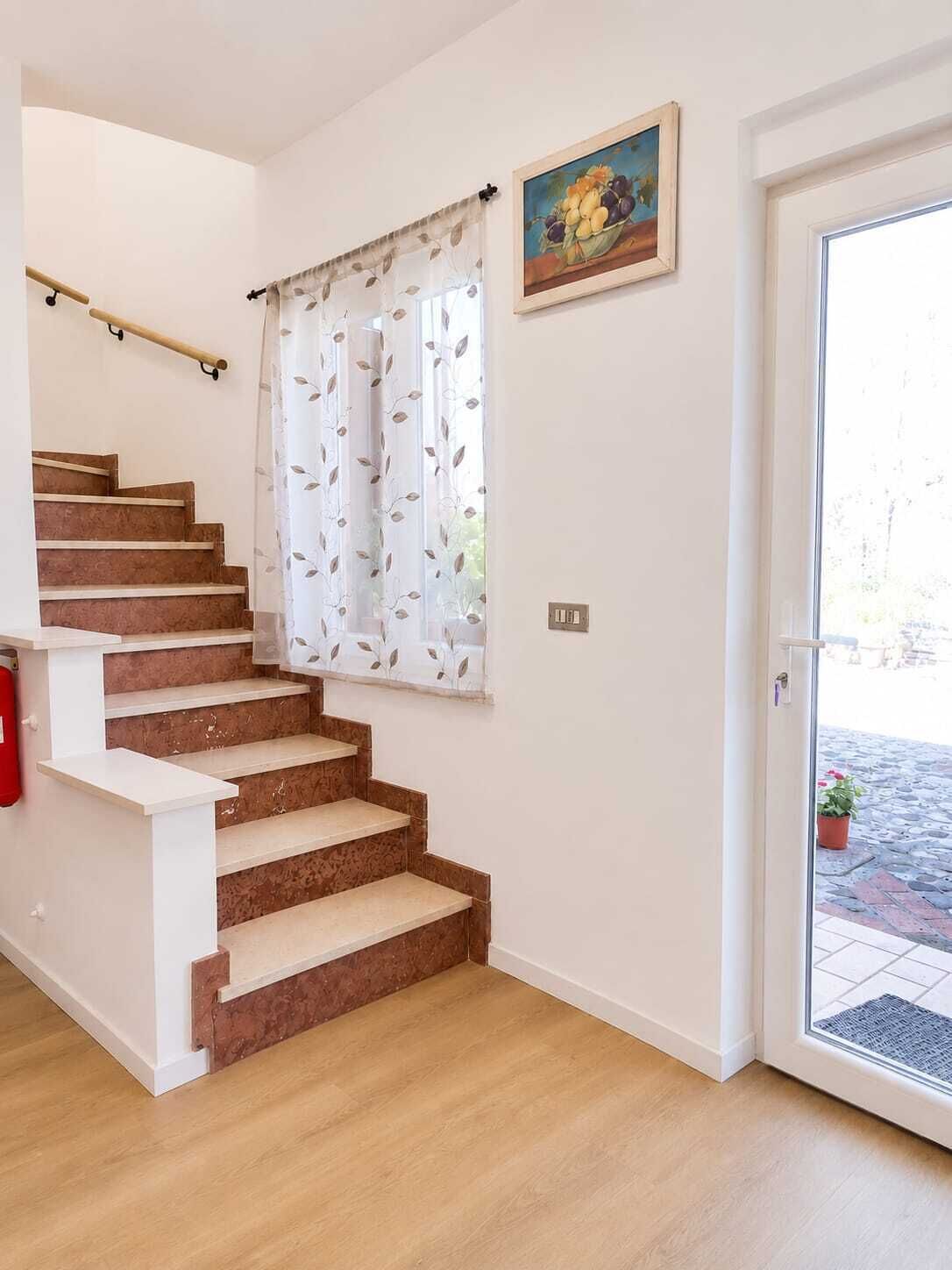 A staircase with a handrail, a door with a glass panel, and a wall-mounted painting.
