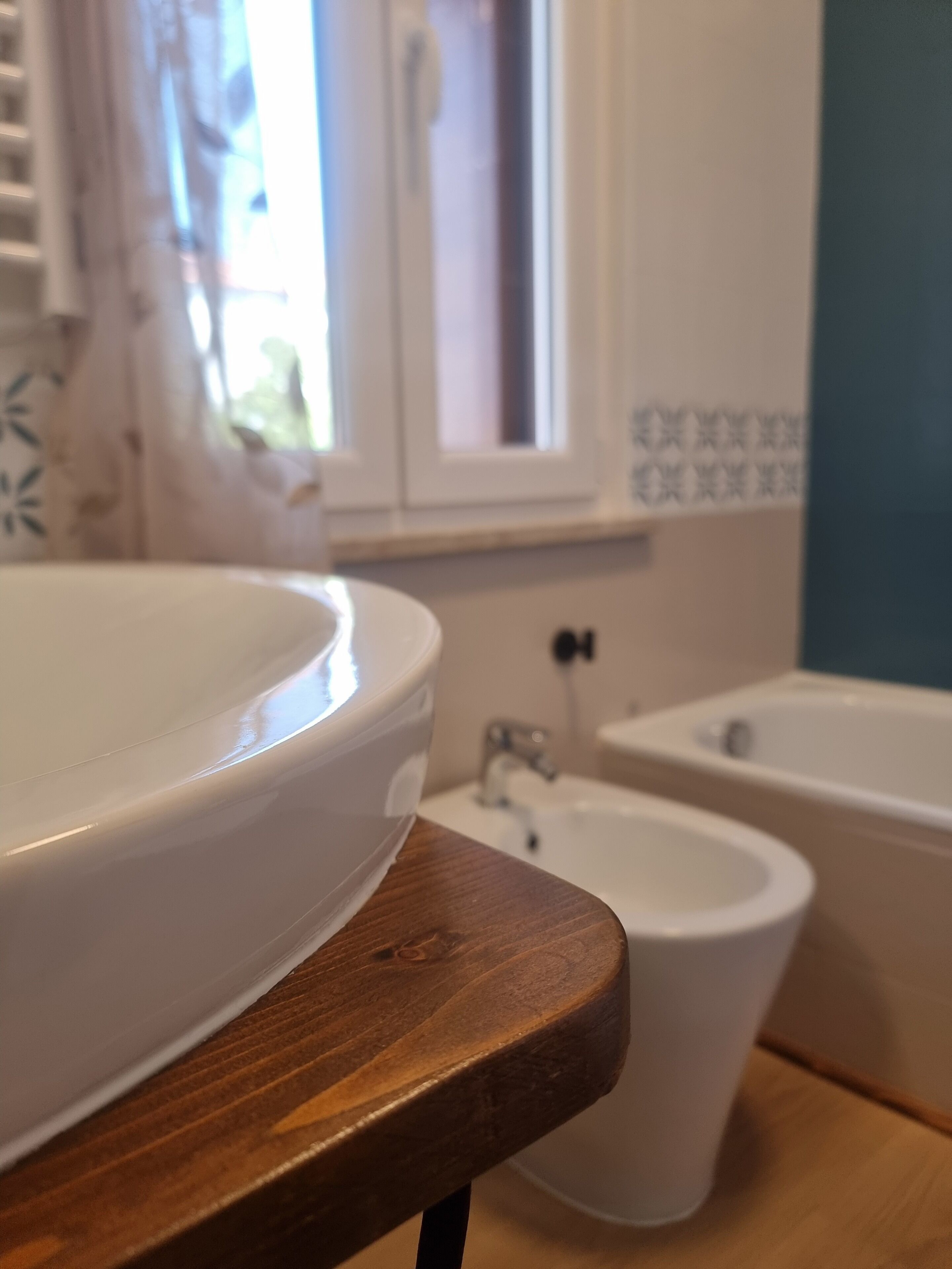 Een badkamer met een houten aanrechtblad, een witte wasbak, een bidet en een bad.