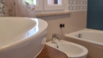 Een badkamer met een houten aanrechtblad, een witte wasbak, een bidet en een bad.