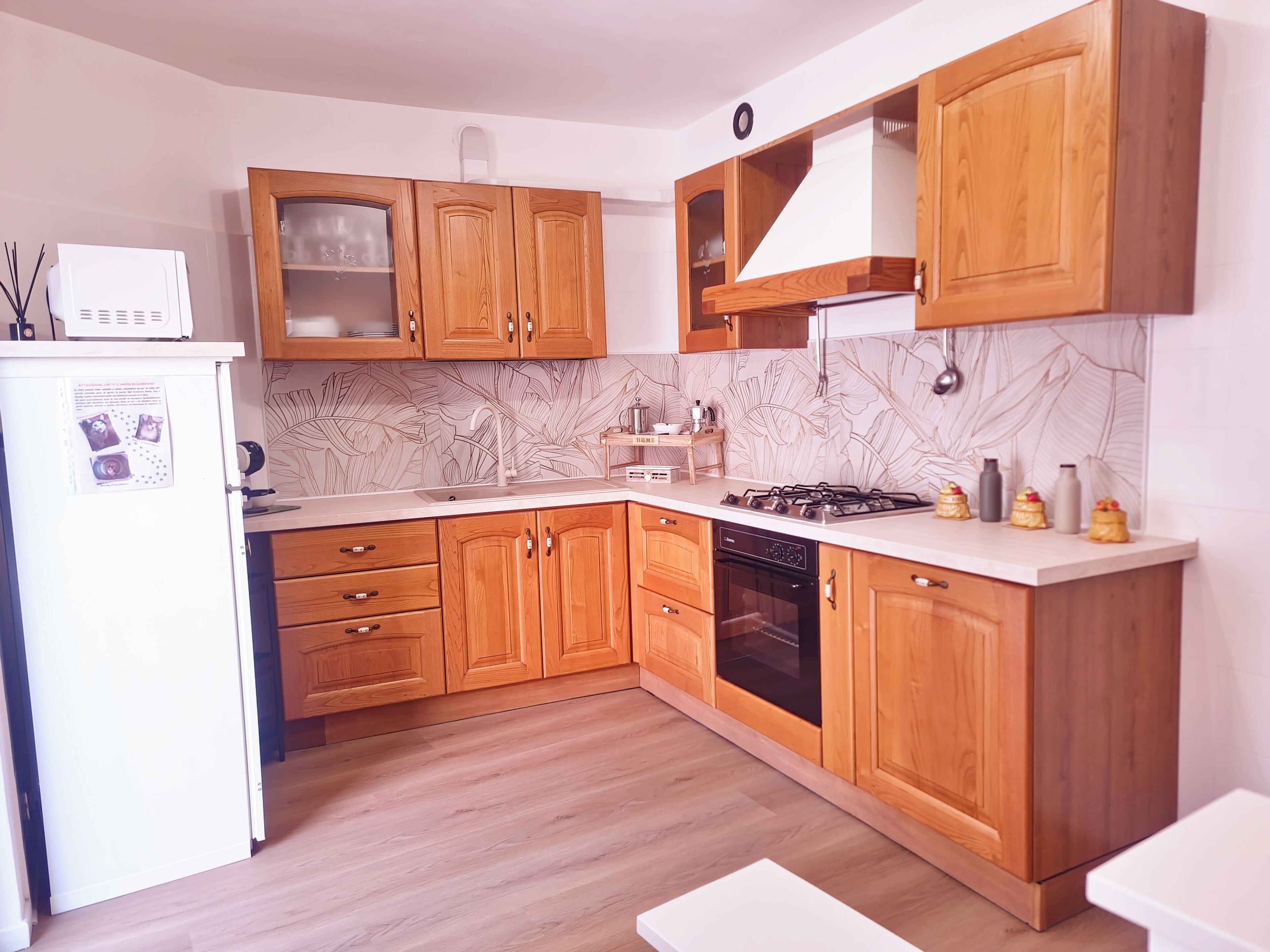 Una cucina con mobili in legno, un frigorifero bianco, un fornello e una lavastoviglie.