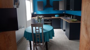 Eine moderne Küche mit blauen Wänden, einem Esstisch mit einem blaugrünen Tischläufer und einem Stuhl.