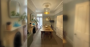 A hallway leading to a dining area with a wooden table, chairs, and a chandelier. - Chic Victorian Home in Forest Gate (Greater London)