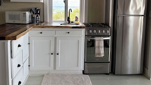 Una cocina con armarios blancos, un refrigerador de acero inoxidable, una estufa y un microondas.