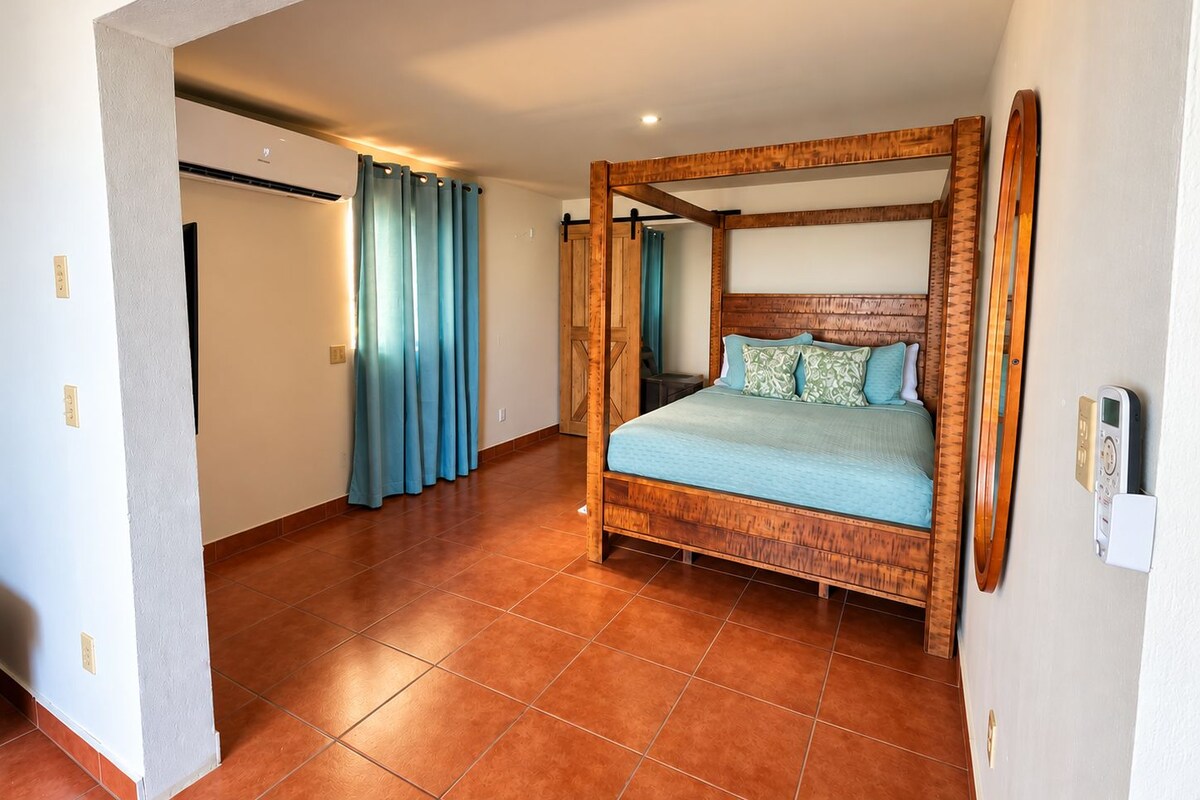 A four-poster bed with a wooden headboard, a blue bedspread, and matching pillows.