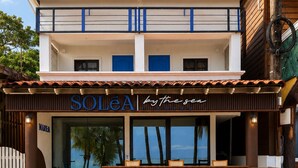 Un edificio de dos pisos con un letrero que dice 'SOLEA by the sea' y vista al océano a través de amplias ventanas.