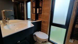 Ein modernes Badezimmer mit einem großen weißen Waschbecken, einer Toilette und einem Spiegel.