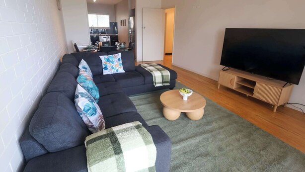 A living room with a sectional sofa, a television, and a small coffee table. - Rockingham Retreat | Right By The Beach (Rockingham)
