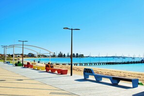 A beach promenade with benches, a pier, and boats in the background. - Rockingham Retreat | Right By The Beach (Rockingham)