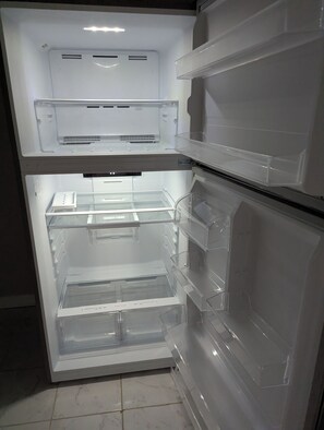 Ein offener Kühlschrank mit mehreren Regalen und Fächern.