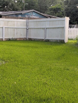 A fenced yard with a grassy area and a building with a sloped roof. - 3-bedroom house in Cantonment (Cantonment)