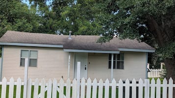 A single-story house with a white picket fence, a front door, and a small porch.