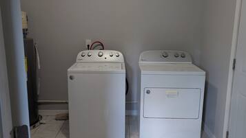 A laundry room with two white Whirlpool washers and dryers, a white ceiling, and a white door.