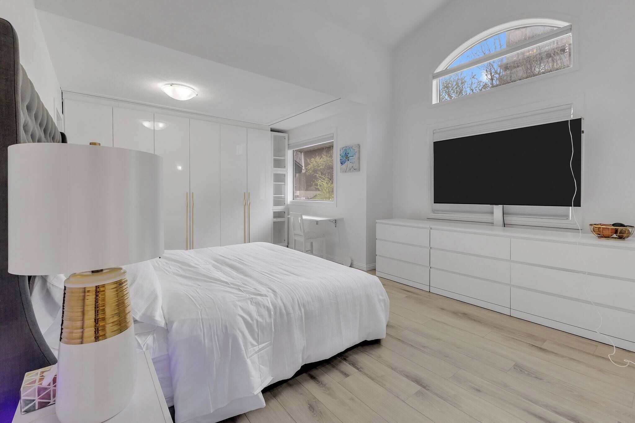 Une chambre à coucher avec un lit, une télévision, une armoire et une fenêtre.