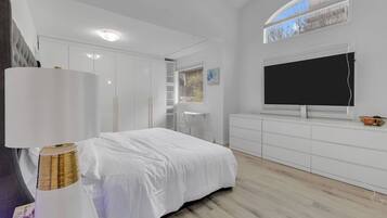 Une chambre à coucher avec un lit, une télévision, une armoire et une fenêtre.