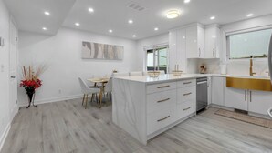 A modern kitchen with white cabinetry, a central island, and a dining area with a table and chairs.