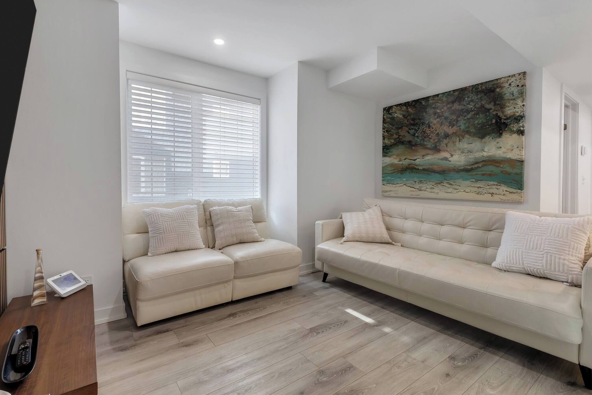 Un salon moderne avec deux canapés, un tableau et un plancher en bois.