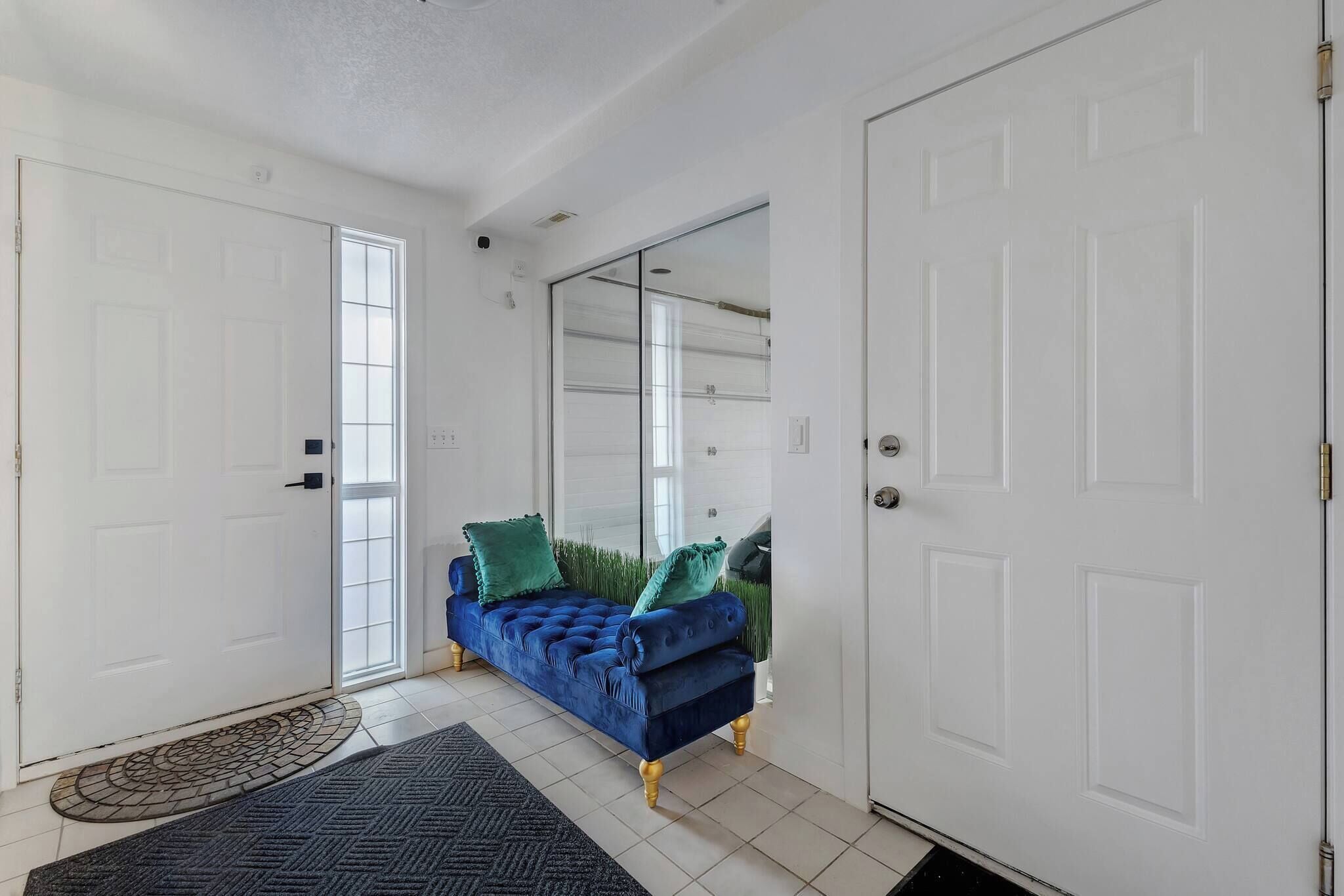 A room with a sofa, a door, a mirror, and a patterned rug.