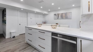 A modern kitchen with white cabinetry, a stainless steel dishwasher, and recessed ceiling lighting.