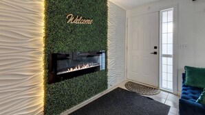 Un interior moderno con chimenea, un cartel de bienvenida y una pared con estampado.