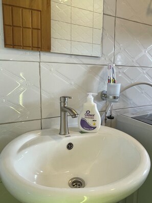 Un lavabo con grifo, dispensador de jabón y portacepillos de dientes.