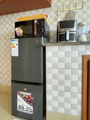 Una cocina equipada con refrigerador, microondas y cafetera.