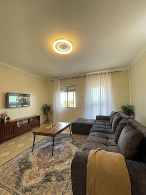 Un soggiorno con un divano, un tavolino, una TV e un tappeto decorato.