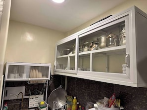 Cuina amb armari encastrat, escorredor i diversos utensilis de cuina.