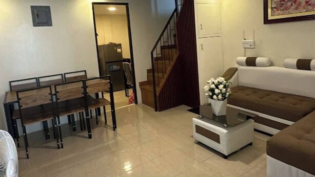Un salon comprenant une table à manger, un canapé et un escalier menant à une autre pièce.