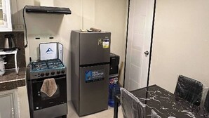 Une cuisine de taille réduite équipée d’une cuisinière, d’un réfrigérateur et d’une table à manger avec des chaises.