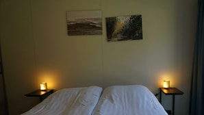 Habitació d'hotel amb un llit, dues taules de nit amb làmpades i dos quadres penjats a la pared.