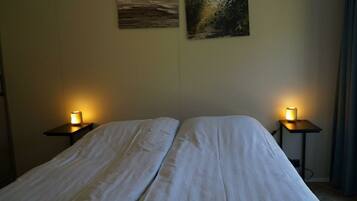 A hotel room with a bed, two bedside tables with lamps, and two wall-mounted paintings.