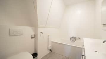 A bathroom with a toilet, bidet, and bathtub.