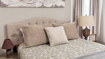A bedroom with a large floral artwork on the wall, a bed with a patterned bedspread, and a bedside lamp.
