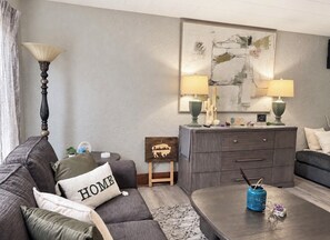 A living room with a sofa, a coffee table, a cabinet, and a lamp.