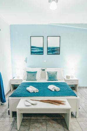 A hotel room with a bed, two bedside tables, a nightstand, a desk, and a chair.