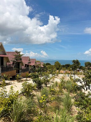 Un hotel frente al mar con varios tejados rojos y un paisaje arenoso.