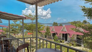 Un área de estar al aire libre con techado, mesas y sillas, con vistas a un paisaje con edificios y árboles.