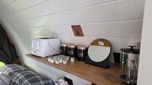 A kitchenette with a toaster, coffee maker, sugar and cream containers, a mirror, and a knife block.