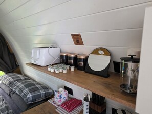 A kitchenette with a toaster, coffee maker, sugar and cream containers, a mirror, and a knife block.