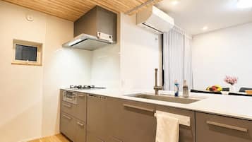 A modern kitchen with wooden ceiling, a built-in oven, and a large mirror.