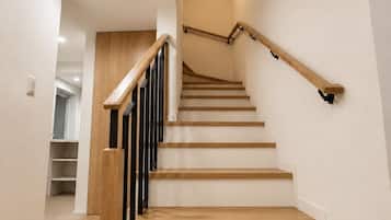 A modern staircase with wooden steps and black handrails, leading to an upper floor.
