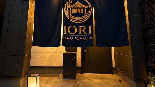 En byggnadsingång med en banderoll som visar namnet ”IORI UENO ASAKUSA”.