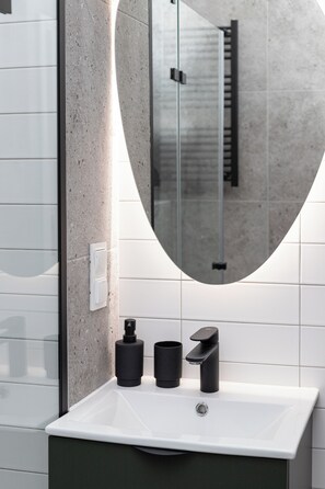 Un baño moderno con un lavamanos blanco, un espejo y un perchero para toallas.