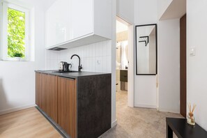A modern kitchen with a wooden island, white cabinets, and a black countertop. - Native Apartments Łazarza 3 (Kraków)